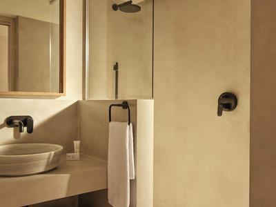 Baño moderno con lavabo, toallero y ducha a ras de suelo en tonos neutros.