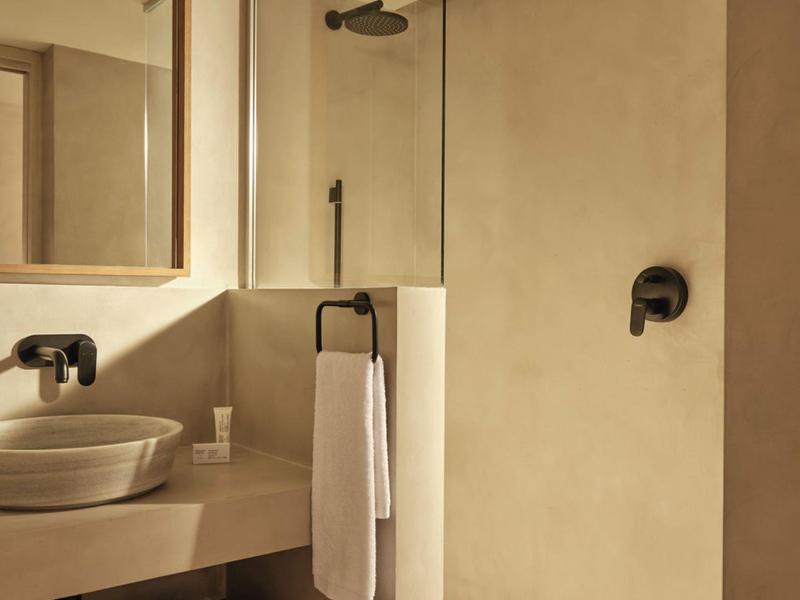 Baño moderno con lavabo, toallero y ducha a ras de suelo en tonos neutros.