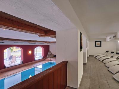 Binnenaanzicht van een wellnessruimte met een zwembad en ligstoelen in de ontspanningsruimte.