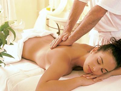 Vrouw ligt ontspannen op massagetafel en krijgt een rugmassage in een lichte kamer.