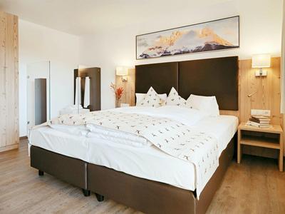 Gezellige hotelkamer met groot bed, houten meubels en abstracte kunst boven het hoofdeinde.