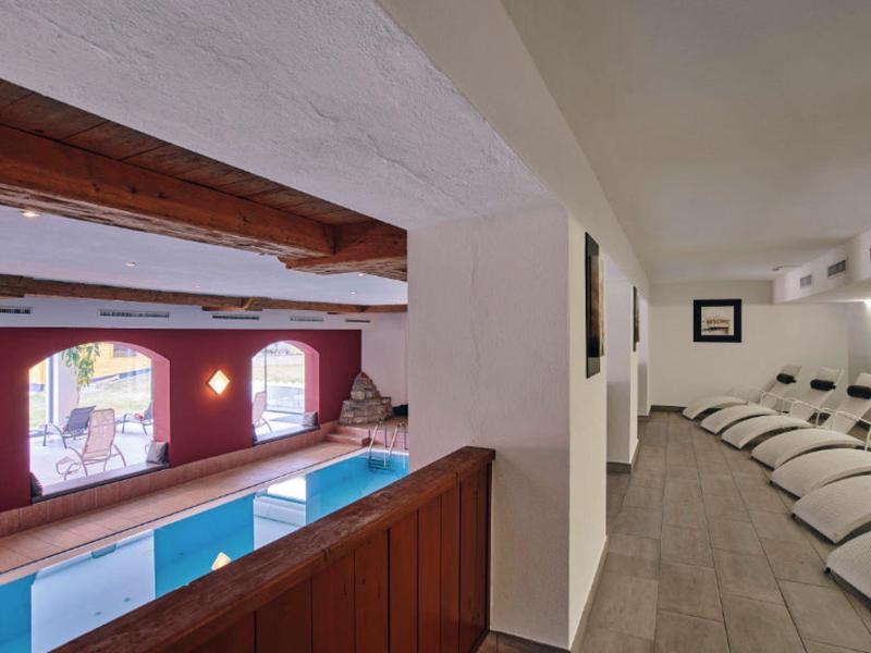 Binnenaanzicht van een wellnessruimte met een zwembad en ligstoelen in de ontspanningsruimte.