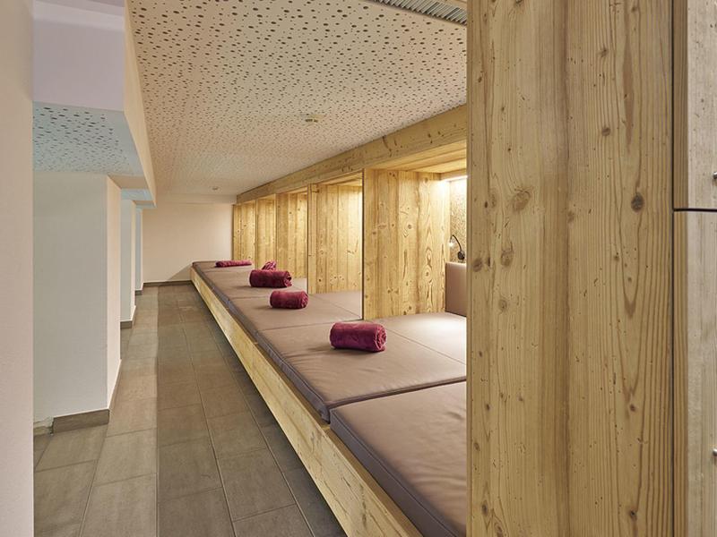 Een moderne ontspanningsruimte met houten panelen en beklede ligbedden, versierd met paarse kussens.