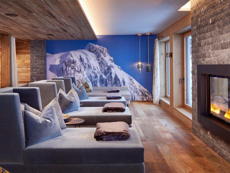 Cozy lounge area with chairs by a fireplace and a mountain image on the wall.