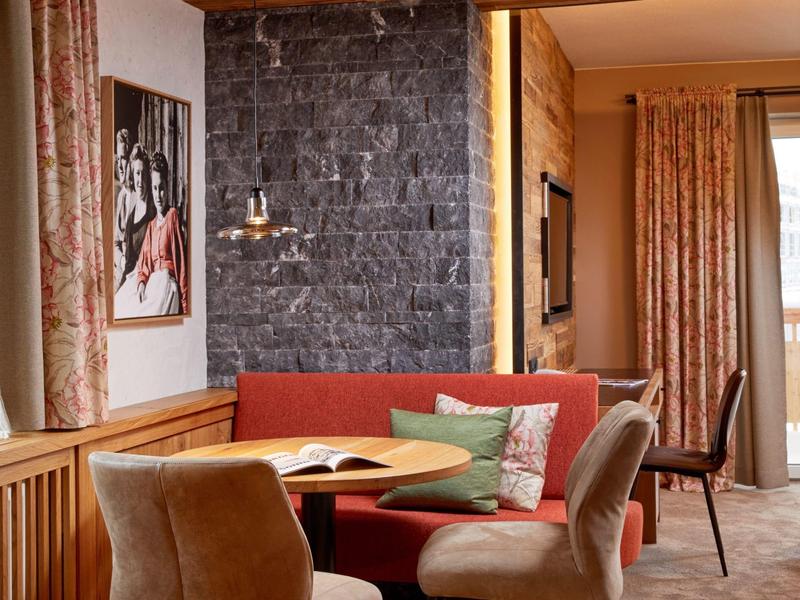 Cozy seating area with red sofa, comfortable chairs, and wood-paneled walls in a hotel room.