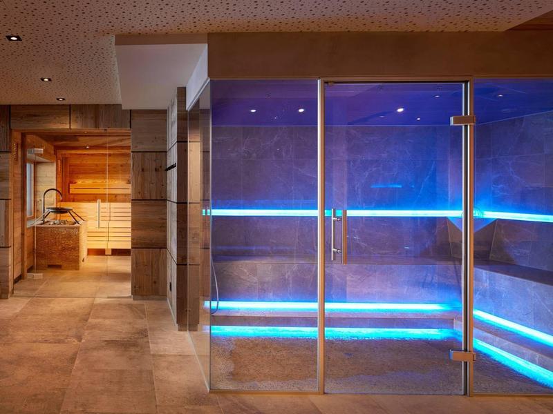 Modern wellness area with sauna and steam room featuring blue LED lighting.