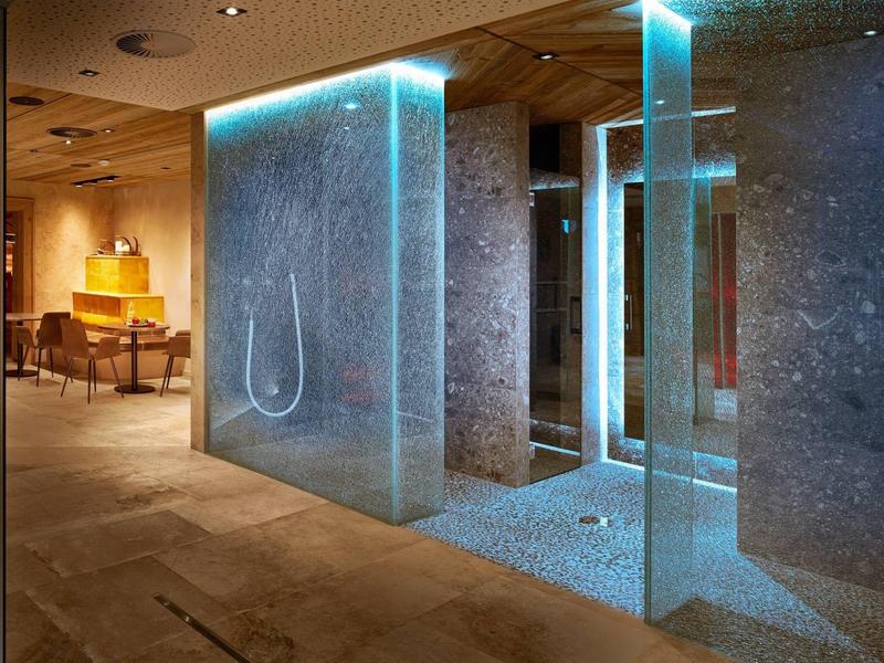 Modern illuminated shower with glass walls in a luxurious hotel bathroom.