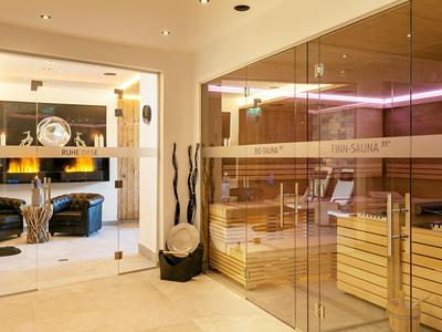 Área de bienestar luminosa con sauna de madera y zona de descanso contigua en un hotel.