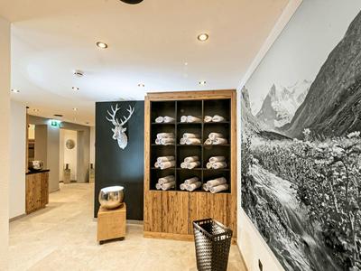 Entrada moderna de hotel con muebles de madera, decoración y paisaje montañoso en la pared.