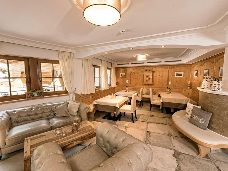 Área de salón acogedora del hotel con sofás de cuero, mesas de madera y cálida decoración de madera.