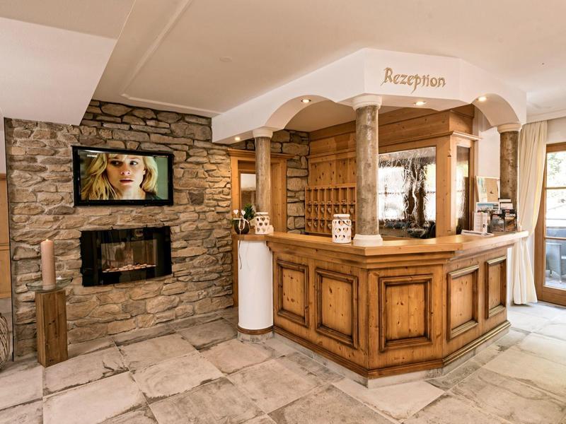 Recepción de hotel acogedora con mostrador rústico de madera y chimenea de piedra en ambiente cálido.