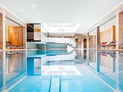 Eleganter Innenpool in modernem Spa-Bereich mit Liegestühlen und hellem Ambiente.
