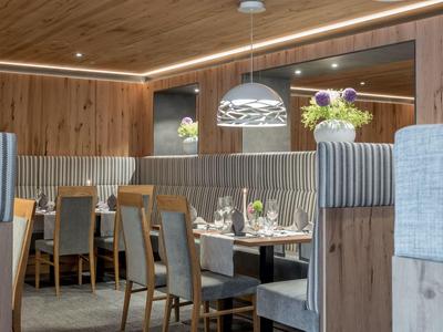 Modernes Restaurant mit Holzvertäfelung, gepolsterten Stühlen und dekorierten Tischen