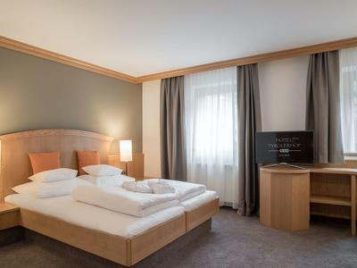 Nowoczesny pokój hotelowy z podwójnym łóżkiem, biurkiem i dwoma oknami.