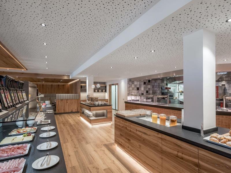 Nowoczesne bufet hotelowy z zimnymi potrawami, otwartą kuchnią i drewnianymi podłogami.