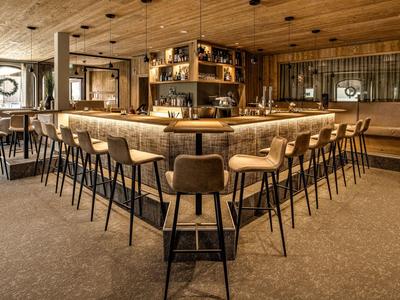 Moderner Barbereich mit hölzernen Elementen und bequemen Barhockern in U-Form.