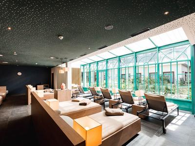 Bright lounge with sun loungers and large windows overlooking a garden.