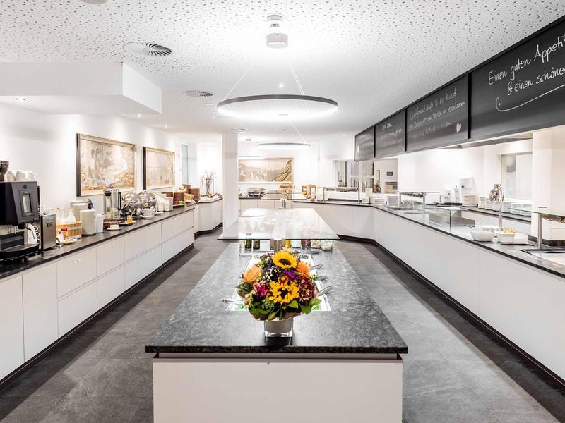 Modern, bright buffet area with central flower arrangement in a hotel.