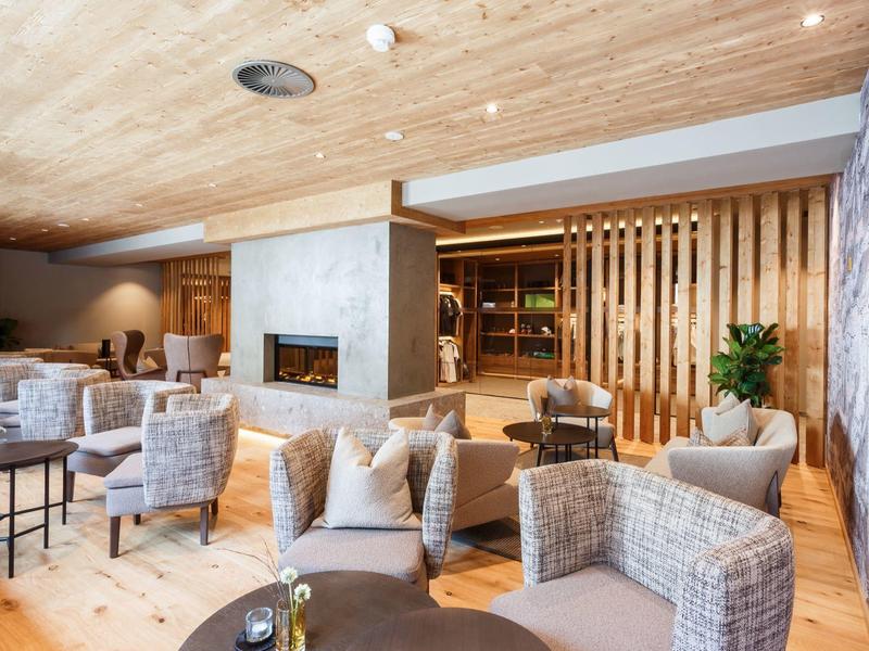 Cozy hotel lounge area with fireplace, comfortable armchairs, and wooden accents.