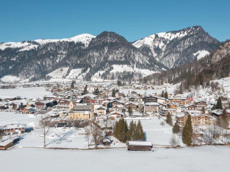 Village in a valley with snow-covered houses and mountains in the background under clear sky