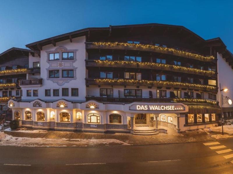 Large mountain hotel with balconies and illuminated entrance at dusk.