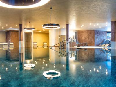 Innenpool mit modernem Design, runden Lichtringen und Treppe im Wellnessbereich.