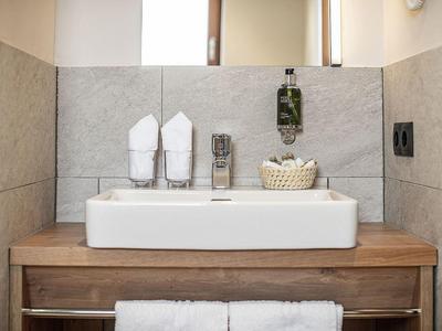 Moderne wastafel met houten blad, witte handdoeken en toiletartikelen.