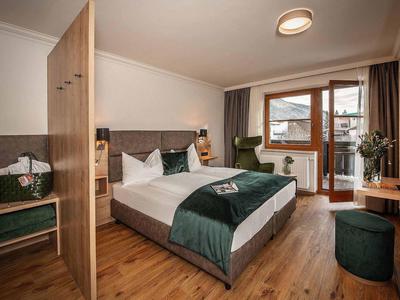 Gezellige hotelkamer met tweepersoonsbed, zithoek en balkon met uitzicht naar buiten.