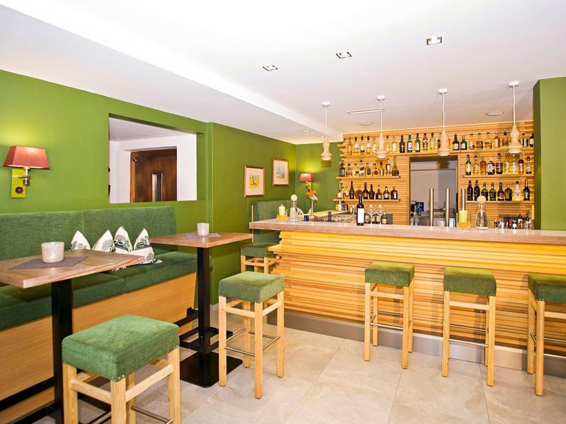 Gezellige bar met groene muren, houten meubels en zachte verlichting.