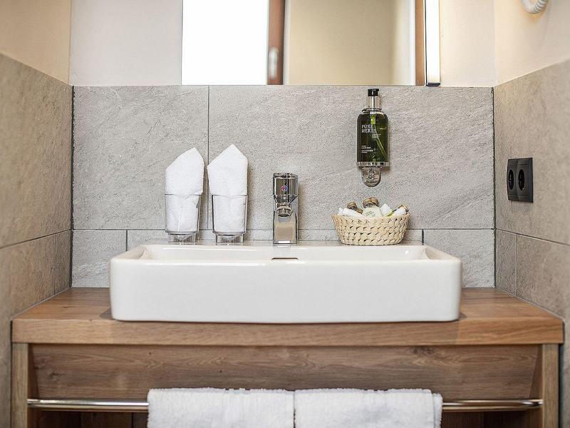 Moderne wastafel met houten blad, witte handdoeken en toiletartikelen.