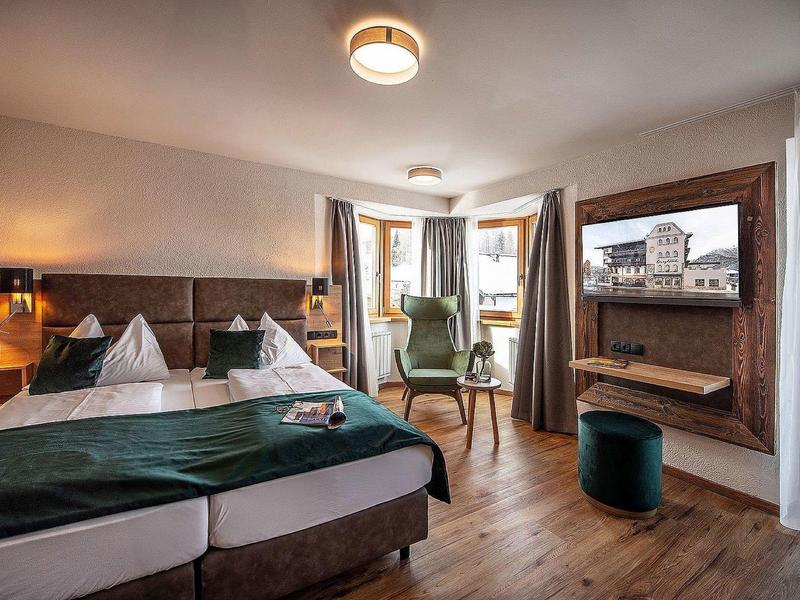 Moderne hotelkamer met tweepersoonsbed, zithoek en aan de muur gemonteerde flatscreen-tv.