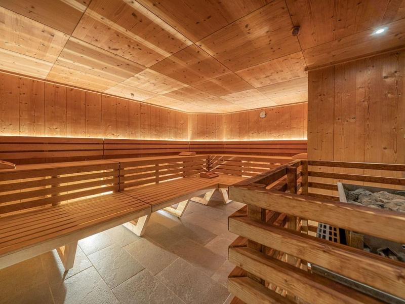 Ruime moderne houten sauna met indirecte verlichting en stenen op de voorgrond.