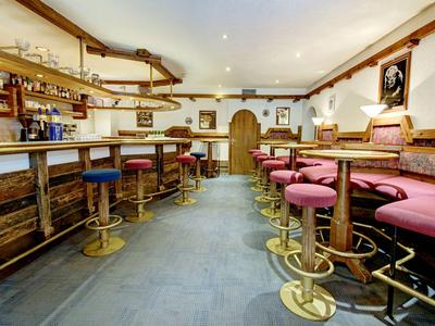 Gemütliche Bar mit hölzernen Möbeln und roten Polsterhockern in einem klassischen Stil.