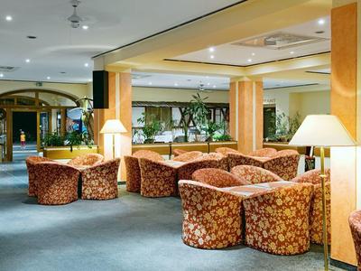 Gemütlicher Hotel-Loungebereich mit floralen Sesseln, Stehlampen und warmen Farben.