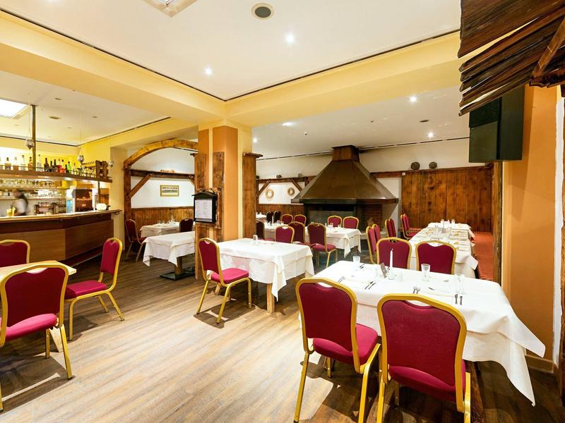 Hell eingerichtetes Restaurant mit roten Stühlen, weißen Tischtüchern und Holzwänden.