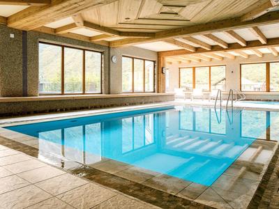 Binnenzwembad met grote ramen en lichte houten balkenplafonds in het hotel.