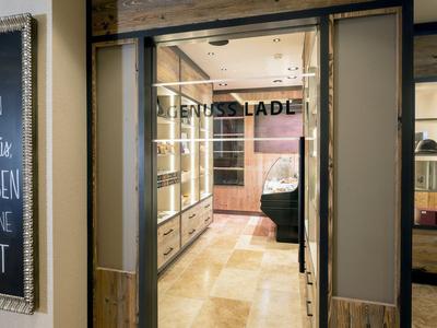 Eingangsbereich eines Ladens mit Glasfront und Tafel mit deutschem Spruch.