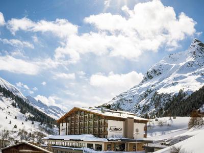 Hotel in besneeuwd berglandschap onder blauwe lucht met felle zon