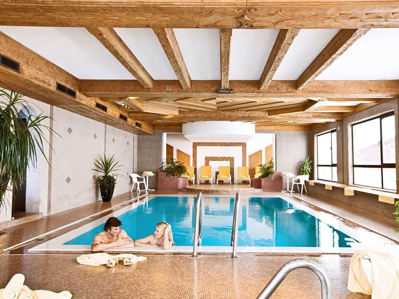 Binnenzwembadkamer met houten plafondbalken en planten naast het water