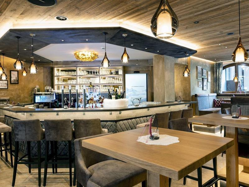 Gezellige hotelbar met houten tafels, bar en moderne verlichting in een warme sfeer.