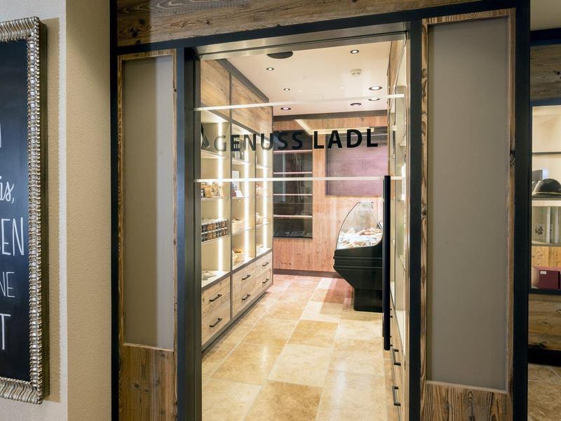 Doorkijkje door glazen deur naar een moderne hotelkamer met bureau en bed.