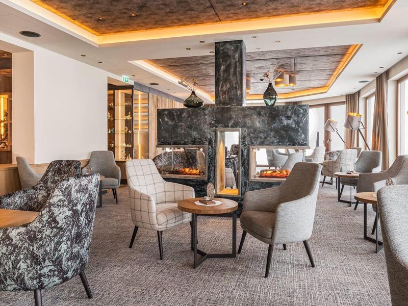 Modern ingerichte hotel lounge met fauteuils, tafels en open haard.