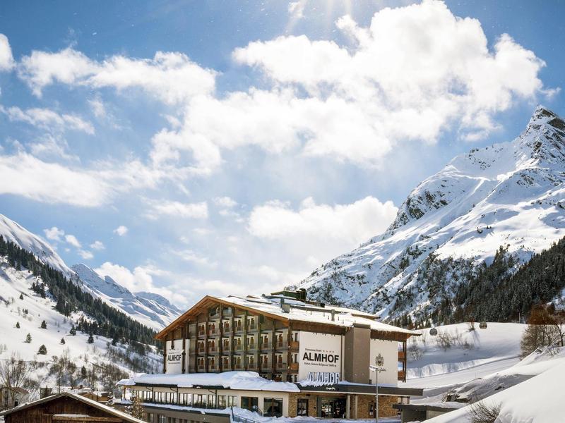Hotel in besneeuwd berglandschap onder blauwe lucht met felle zon