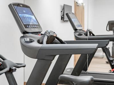Moderner Fitnessraum mit Laufband und Spiegelfront in einem Hotel.