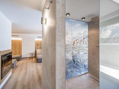 Modern shower area with glass wall and open living area featuring fireplace and wooden floor