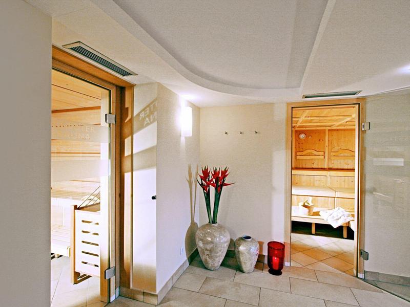 Interior of a modern sauna with light tiles and plant decoration.