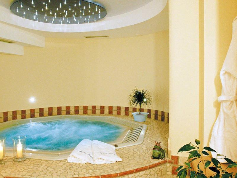 Round whirlpool with warm lighting, candles, and bathrobes in a wellness area.