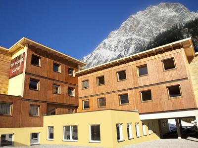 Multi-story wooden hotel building with mountain backdrop under clear sky