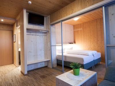 Modern hotel room with wooden walls, double bed, and built-in TV in cabinet