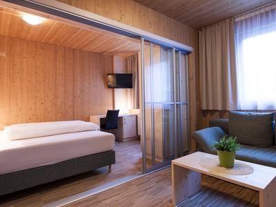 Modern hotel room with wooden walls and separate sleeping and living areas.